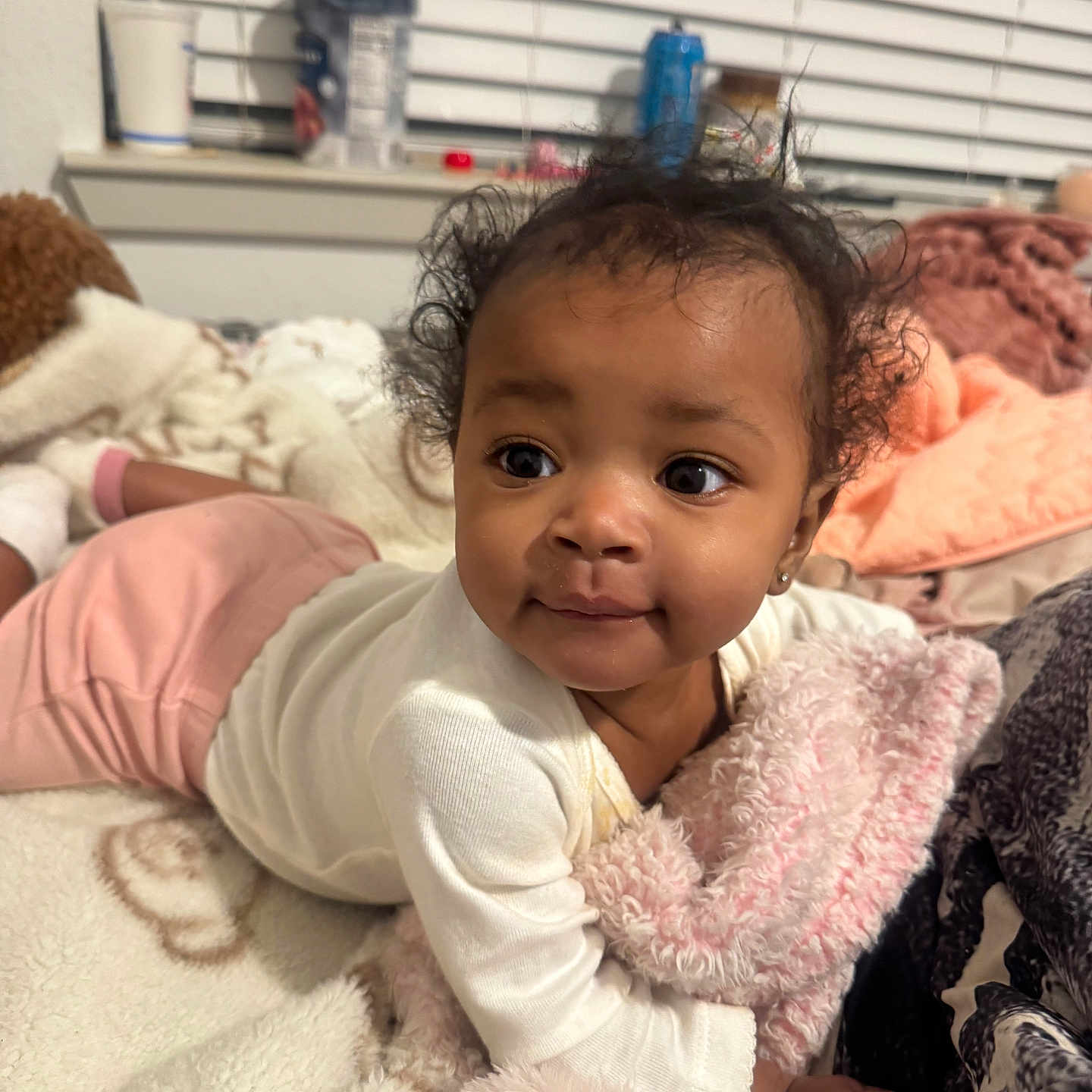 Alaia joined the competition — help win amazing prizes! baby, bed, blanket, child, cozy, curly_hair, cute, face, home, indoors, infant, lying_down, person, pink_pants, plush, portrait, smiling, soft_texture, white_shirt, window_blinds