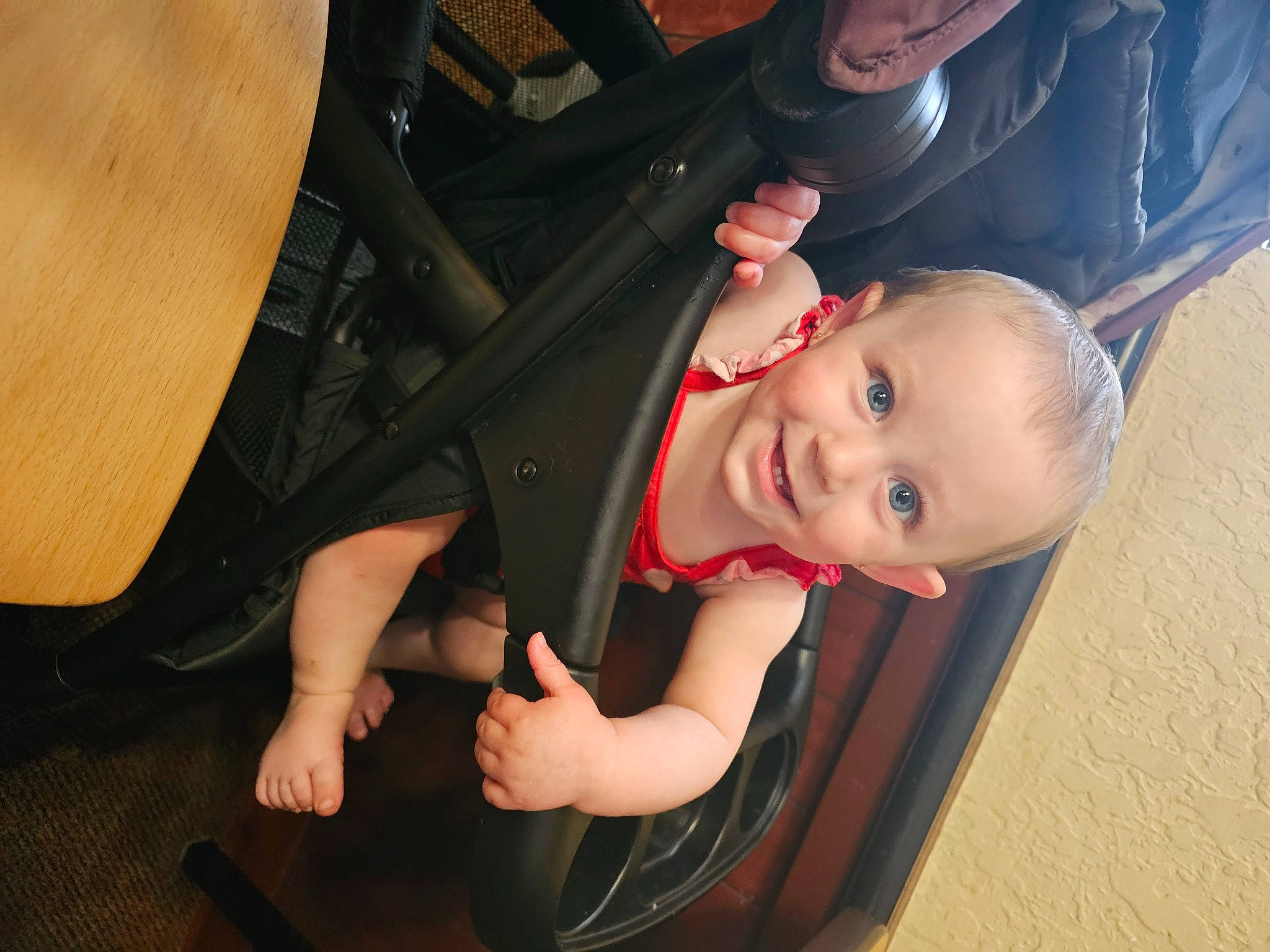 Maria is registered to the contest to win money with this photo: arm, auto_part, automotive_tire, baby, baby_carriage, chair, comfort, eye, flash_photography, fun, joy, leg, mouth, person, product, skin, smile, thigh, tire, toddler