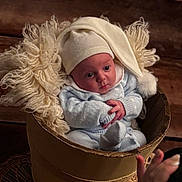 Jonas participe au concours pour gagner de l'argent avec cette photo : baby, infant, knitwear, hat, bucket, wool, yarn, cozy, cute, portrait, indoors, wood, woven_mat, hand, photography, child, newborn, soft_lighting, expression, curious
