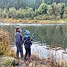 adult, beard, boots, child, family, fishing_rod, forest, grass, hat, hobby, jacket, nature, outdoor, overcast, recreation, river, rocks, scenery, trees, water