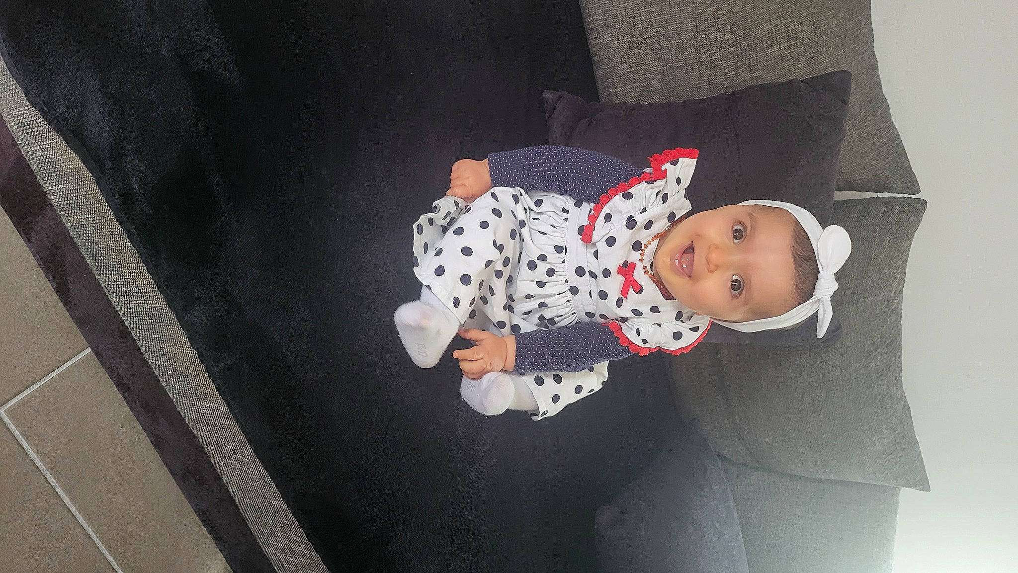 Louisa a rejoint le concours — aidez-le/la à gagner de superbes lots ! baby, baby_products, baby_toddler_clothing, carmine, child, comfort, flooring, fun, hat, linens, pattern, person, room, sitting, sleeve, smile, toddler, wood