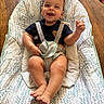 baby, smiling, child, infant, baby_chair, seatbelt, patterned_fabric, wooden_floor, happy, sitting, indoors, cute, person, face, hand, foot, clothing, home, comfort, expression