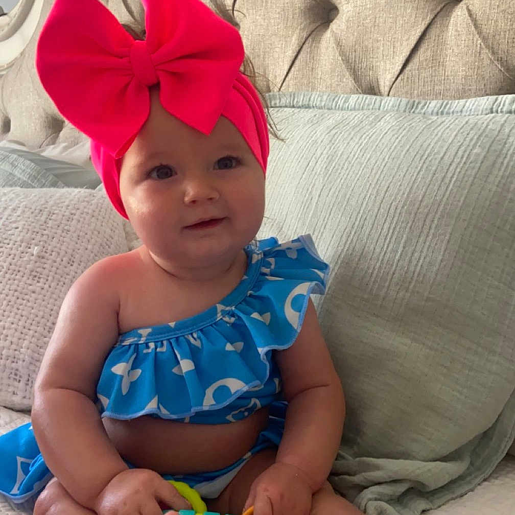 Riverlyn is registered to the contest to win money with this photo: baby, bed, bonnet, cap, clothing, costume, couch, cushion, dress, face, furniture, hat, head, homedecor, indoors, person, photography, portrait, scissors, swimwear