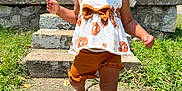Zaylee is registered to the contest to win money with this photo: toddler, child, smiling, outdoor, sunny, grass, steps, house, sidewalk, sandals, hair_bows, shorts, top, shadow, concrete, happy, walking, summer, portrait, person