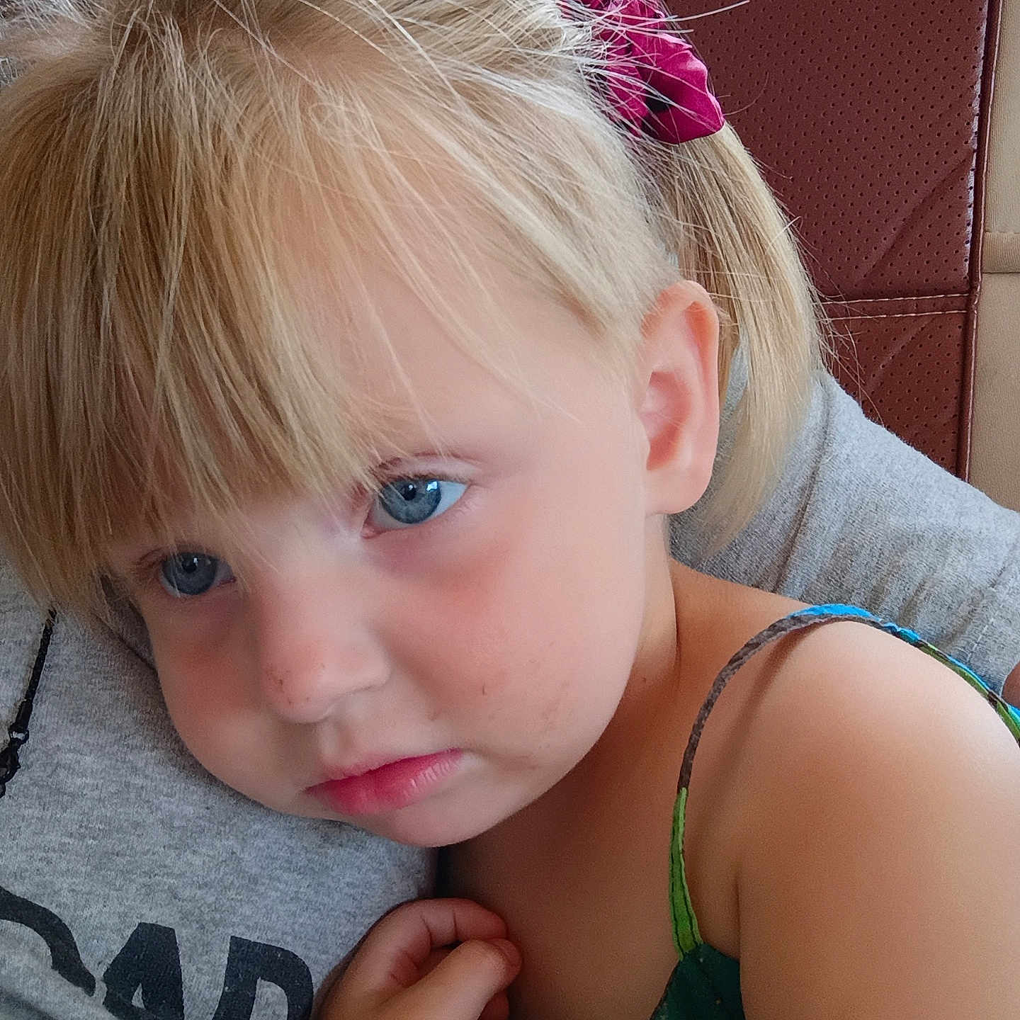 Azora is registered to the contest to win money with this photo: child, girl, toddler, portrait, close_up, blue_eyes, blonde_hair, hair_bow, pouting, face, indoors, car, car_seat, adult, cuddling, shoulder, dress, hand, photography, family