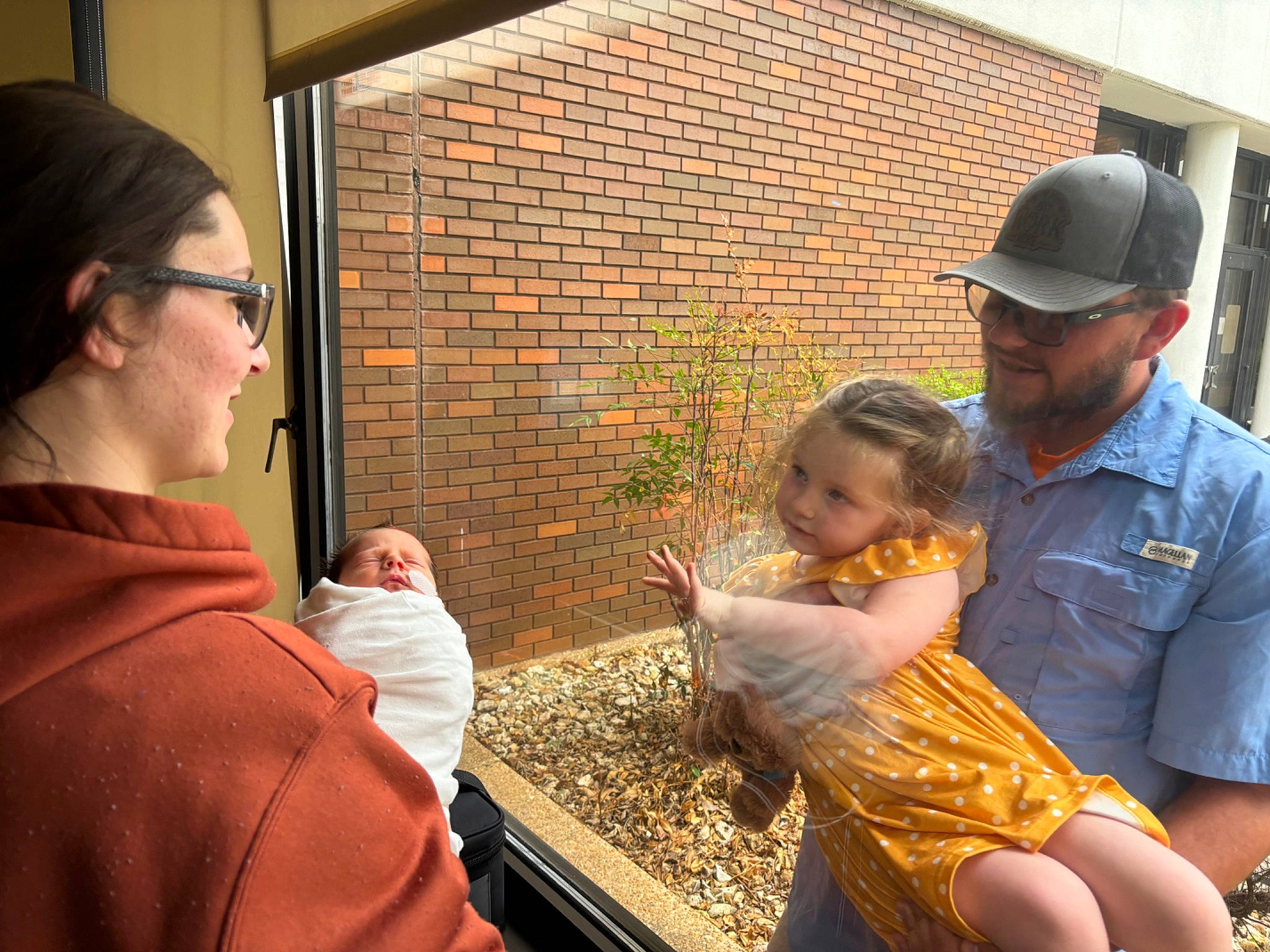 Stella is registered to the contest to win money with this photo: adaptation, baby, baseball_cap, cap, child, conversation, event, eyewear, fun, grass, hat, headwear, hoodie, joy, leisure, people, person, recreation, sitting, soil