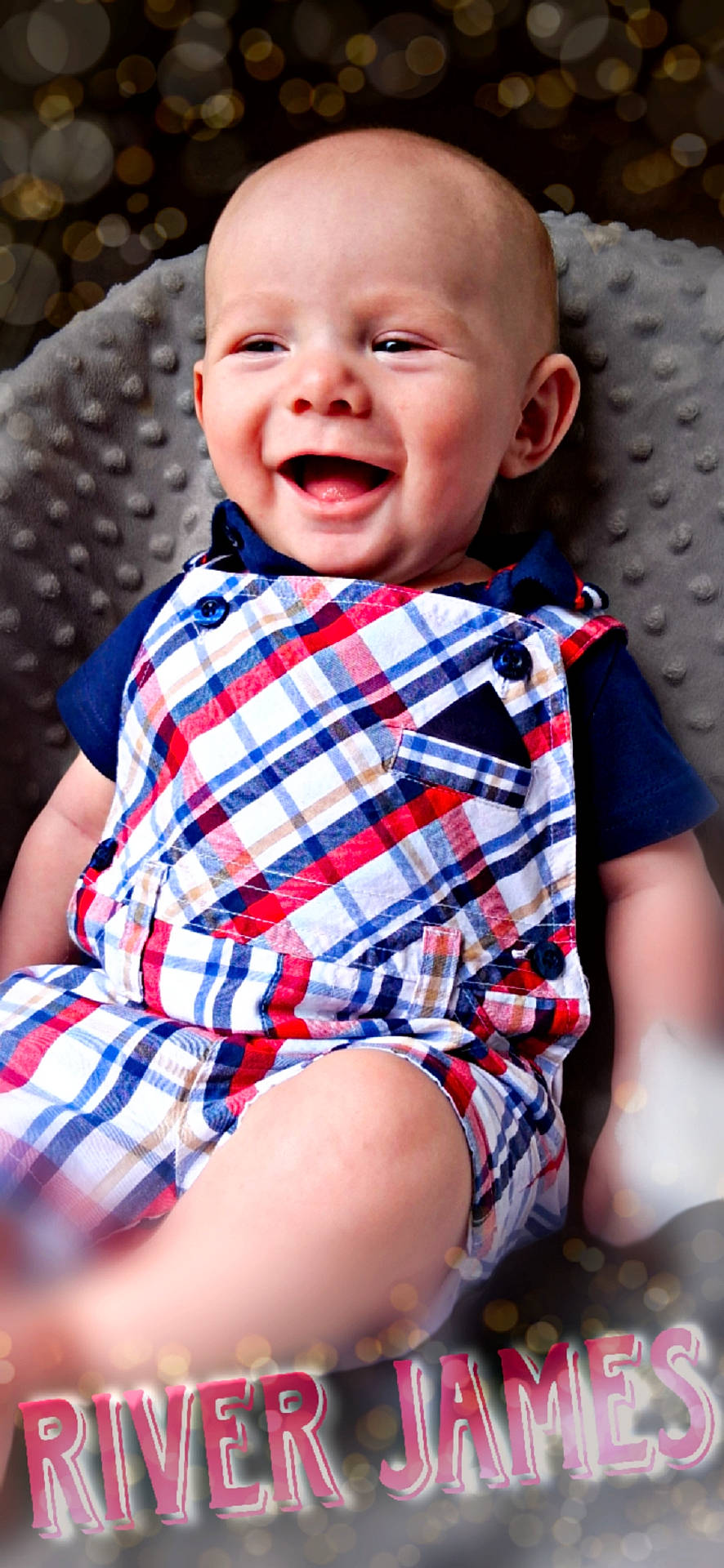 River joined the competition — help win amazing prizes! baby, background, bokeh, bright, child, colorful, cushion, cute, face, gray, happy, head, indoor, infant, person, plaid_clothing, portrait, romper, sitting, smiling