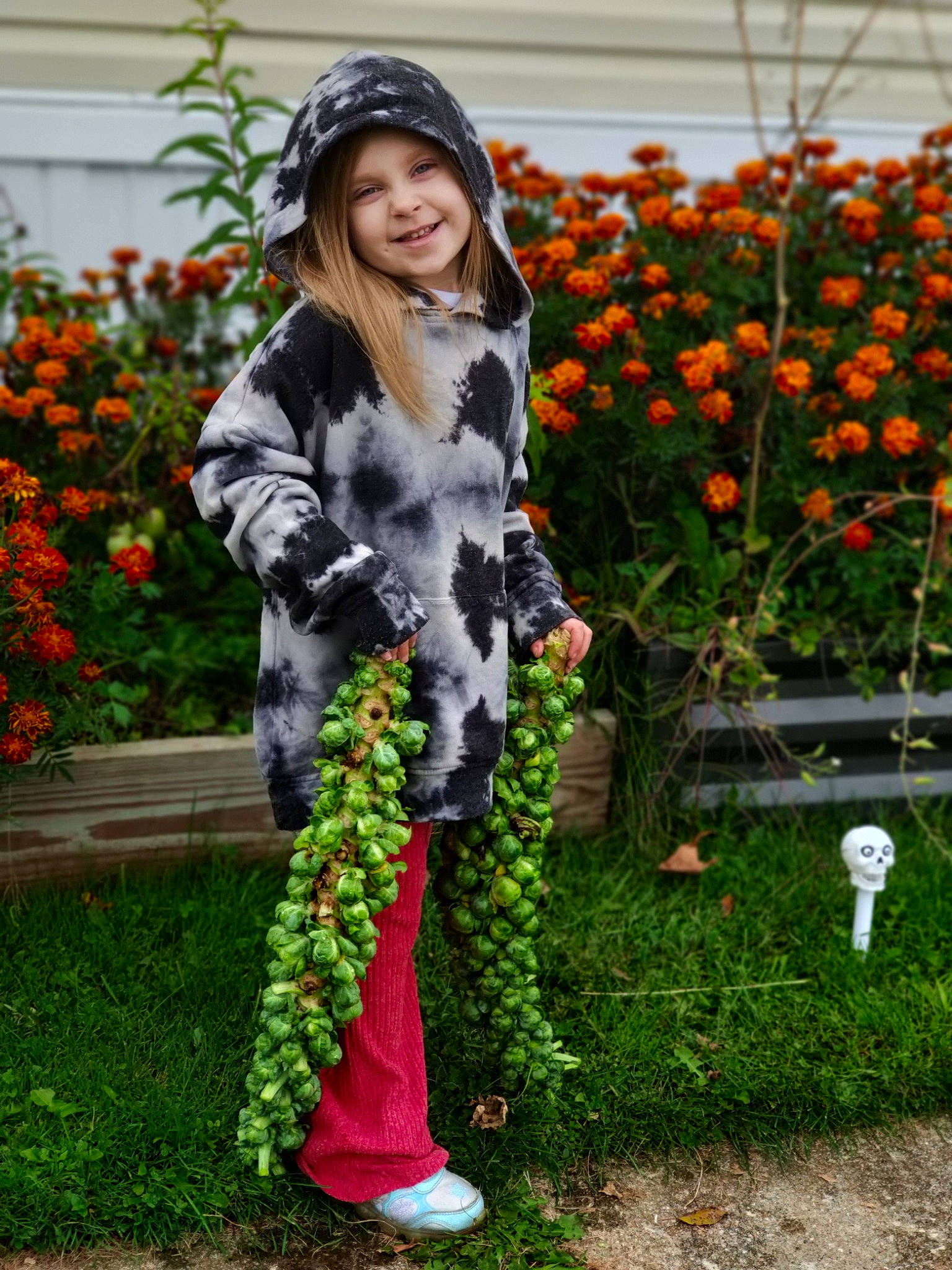 Lillith is registered to the contest to win money with this photo: annual_plant, boot, cap, denim, face, fashion_accessory, floral_design, flower, garden, grass, headwear, human_leg, joy, knee, orange, pattern, person, plant, pumpkin, shoe