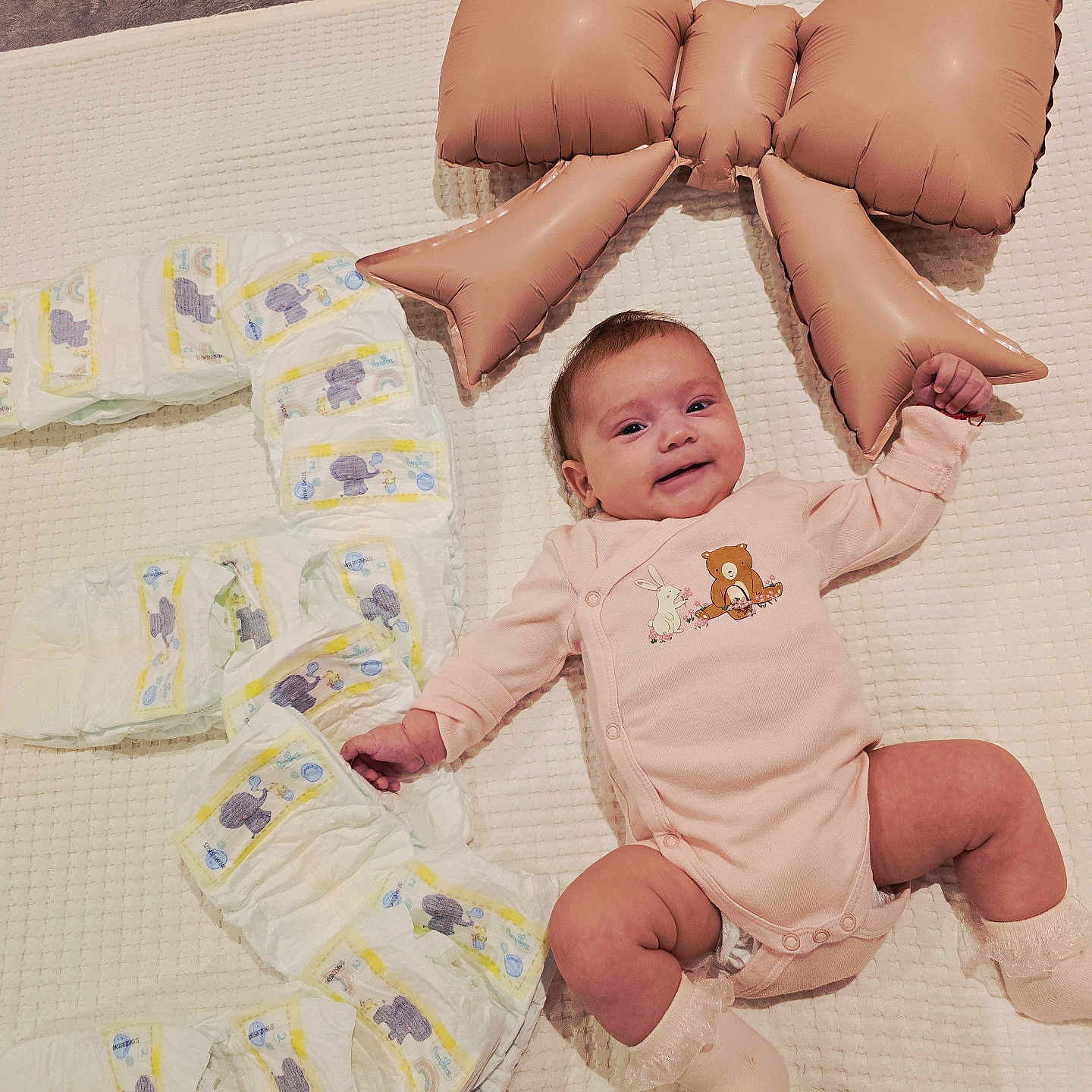 Selena is registered to the contest to win money with this photo: adorable, baby, baby_face, baby_sock, celebration, child, cute, diapers, happy, indoor, infant, inflatable_bow, lying_down, milestone, number_three, onesie, pink_clothing, smiling, soft_texture, white_blanket