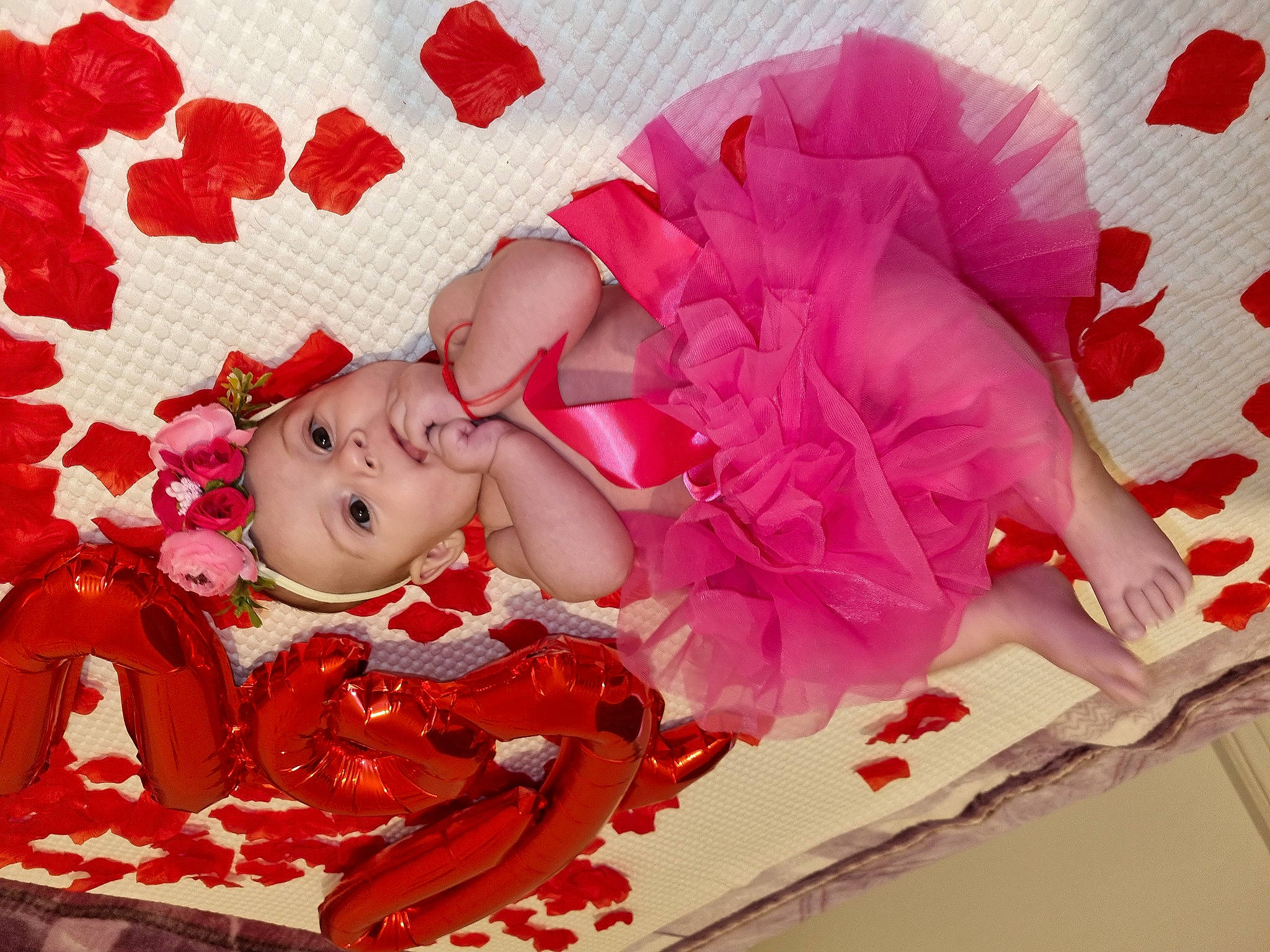 Giulia is registered to the contest to win money with this photo: baby, baby_toddler_clothing, carmine, child, cut_flowers, doll, embellishment, fashion_accessory, hair_accessory, happy, headpiece, headwear, magenta, pattern, peach, person, petal, pink, rose, sweetness