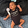 Zymirah is registered to the contest to win money with this photo: baby, infant, onesie, pacifier, bow, blue_bow, black_onesie, blanket, fabric, lying_down, cute, necklace, raised_fist, infant_clothing, newborn, skin, foot, hand, portrait, child
