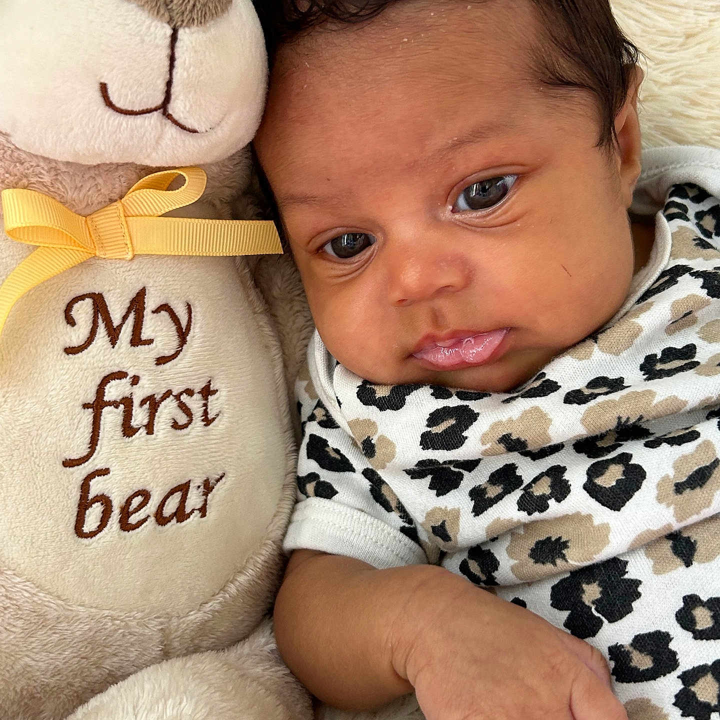 Zymirah is registered to the contest to win money with this photo: baby, infant, plush_toy, teddy_bear, leopard_print, clothing, cute, soft_toy, ribbon, close_up, portrait, child, sleepwear, cozy, animal_print, fabric, face, hand, lying_down, indoors