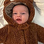 baby, infant, child, cute, smiling, tongue_out, bear_costume, hood, fuzzy_clothing, soft_texture, white_blanket, portrait, closeup, happy, lying_down, warm_clothing, adorable, face, head, expressive
