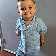 Nathan participe au concours pour gagner de l'argent avec cette photo : blue_jumpsuit, boy, casual_clothing, child, cute, dimples, door, fashion, floor, happy, indoor, person, playful, portrait, short_hair, smile, standing, toddler, white_sneakers, young
