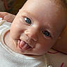 baby, infant, tongue_out, blue_eyes, white_clothing, cute, face, smiling, person, child, portrait, cheeky, indoors, closeup, skin, young, head, expression, happy, playful