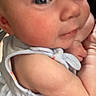 Logan is registered to the contest to win money with this photo: baby, infant, face, skin, blue_clothing, floral_pattern, chubby_cheeks, eyes, arm, hand, person, closeup, cute, child, newborn, holding, soft_skin, indoor, portrait, expression