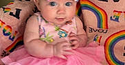 Logan is registered to the contest to win money with this photo: baby, child, pink_dress, bow, headband, rainbow_blanket, colorful, cute, infant, sitting, portrait, indoors, soft_toys, chubby_cheeks, clothing, patterned, happy, person, young_child, baby_girl