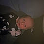 Ava is registered to the contest to win money with this photo: baby, infant, face, clothing, heart_pattern, blanket, dark, indoor, person, newborn, sleepwear, cute, lying_down, child, soft_light, portrait, young, baby_girl, cozy, expression