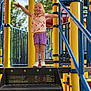 Everlee is registered to the contest to win money with this photo: child, playground, stairs, yellow_poles, blue_railings, outdoor, smiling, shorts, tshirt, sneakers, sunny, trees, daytime, happy, person, recreation, play, summer, fun, park
