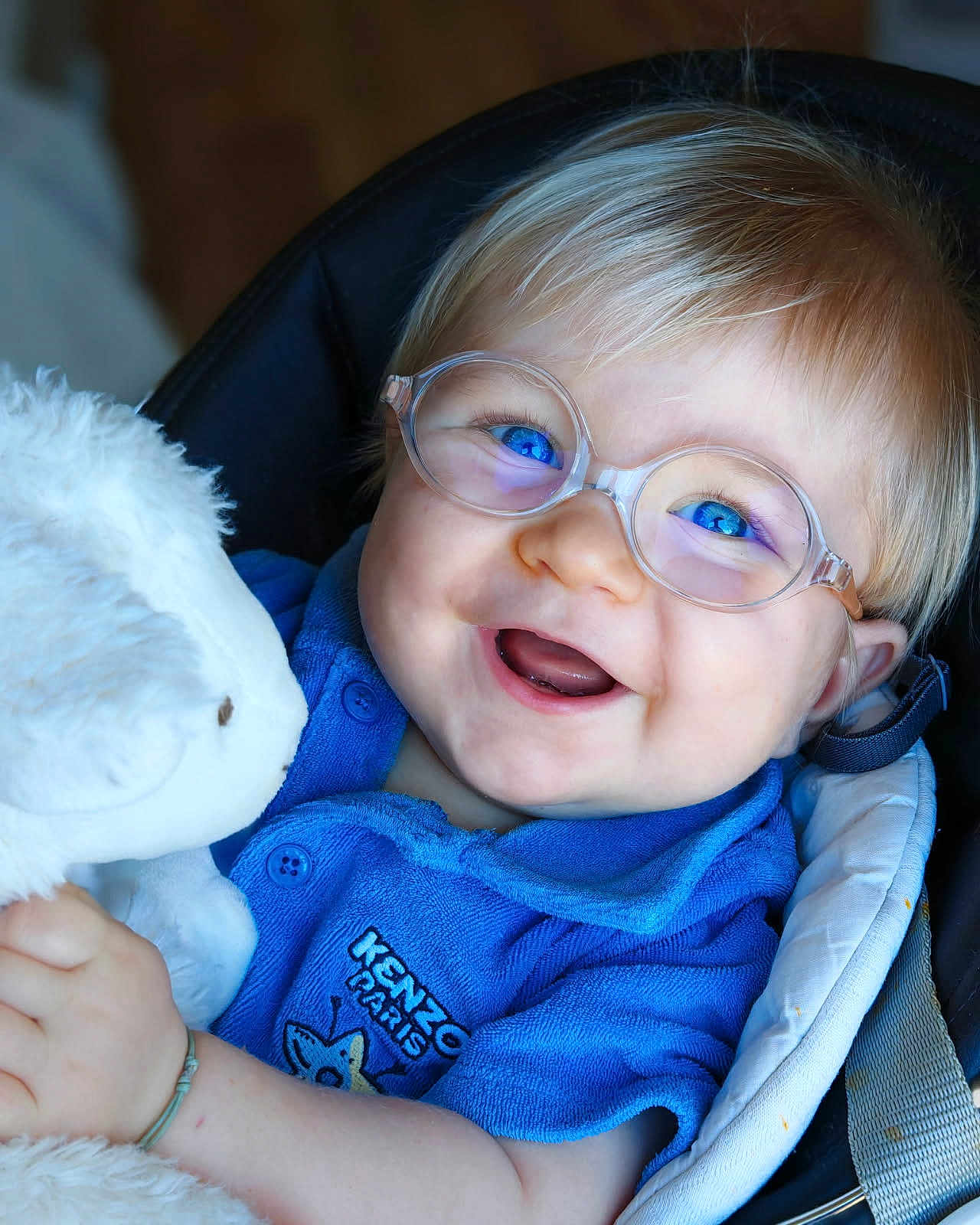 Don Carlu a rejoint le concours — aidez-le/la à gagner de superbes lots ! baby, child, glasses, blue_eyes, smiling, teddy_bear, plush_toy, blue_shirt, seated, cushion, happy, portrait, cute, infant, closeup, indoor, person, soft_toy, clothing, accessory