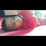 Alvaro joined the competition — help win amazing prizes! baby, child, smiling, red_clothing, lying_down, indoor, face, cute, infant, playful, person, portrait, young_child, bed, blanket, soft_light, happy, looking_up, skin, head