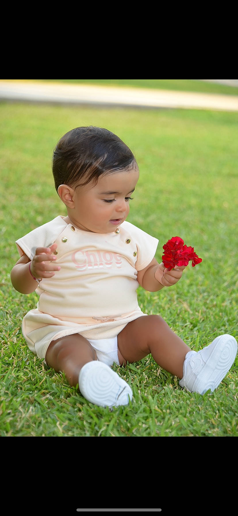 Aliyah participe au concours pour gagner de l'argent avec cette photo : baby, baby_toddler_clothing, face, facial_expression, finger, flower, gesture, grass, grassland, happy, leg, leisure, people_in_nature, person, pink, plant, shoe, skin, sneakers, thigh
