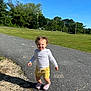 Elyana is registered to the contest to win money with this photo: toddler, child, smiling, curly_hair, white_shirt, yellow_shorts, pink_crocs, outdoor, sunny, blue_sky, green_trees, asphalt_path, crack, grass, summer, happy, person, nature, daylight, portrait