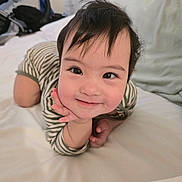 Muslima joined the competition — help win amazing prizes! baby, child, smiling, striped_clothing, bed, pillow, hand, face, portrait, cute, indoors, person, toddler, happy, skin, hair, lying_down, infant, cozy, expression