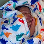 Josiah joined the competition — help win amazing prizes! baby, sleeping, blanket, dinosaur_pattern, cozy, infant, soft_fabric, colorful, cute, wrapped, rest, peaceful, child, indoors, portrait, newborn, comfort, warm, face, hand