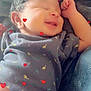 Josiah joined the competition — help win amazing prizes! baby, newborn, smiling, sleeping, blanket, clothing, dinosaur_pattern, heart_overlay, cute, infant, soft_texture, cozy, happy, resting, child, person, indoor, portrait, small_hands, peaceful