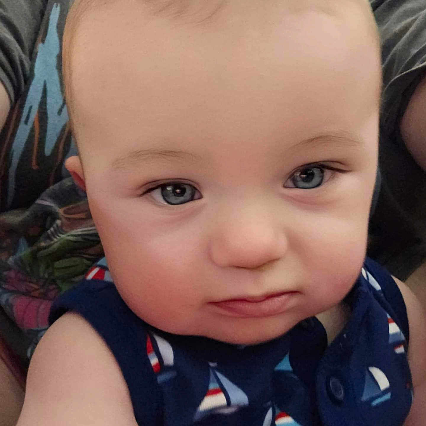 Jensen is registered to the contest to win money with this photo: baby, child, face, blue_eyes, sailboat_pattern, sleeveless_outfit, curious_expression, close_up, selfie, person, skin, hair, indoor, casual_clothing, cute, infant, portrait, human, young, looking_at_camera