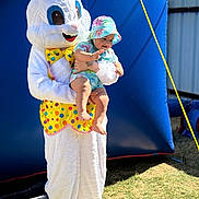 David is registered to the contest to win money with this photo: baby, child, easter_bunny, costume, outdoor, sunny, grass, blue_backdrop, hat, colorful_clothing, person, holding, smiling, festival, celebration, playful, cute, fun, event, holiday