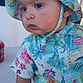 David is registered to the contest to win money with this photo: toddler, child, hat, bucket_hat, floral_pattern, shirt, short_sleeves, outdoor, daylight, curious, closeup, portrait, sitting, bracelet, skin, face, eyes, person, summer, colorful_clothing