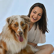 Ulyss participe au concours pour gagner de l'argent avec cette photo : woman, dog, smiling, happy, pet, friendship, sitting, indoor, casual, cute, long_hair, white_clothing, furry, tongue_out, light_background, relaxed, companion, animal, portrait, playful