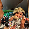 baby, smiling, camo_hat, onesie, adult_hands, outdoor, night, tent, people, gathering, table, food, drinks, casual, portrait, happy, cute, infant, holding, celebration