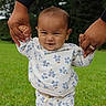 baby, child, infant, grass, outdoor, nature, hands, support, walking, clothing, floral_pattern, smile, person, blanket, greenery, cute, toddler, playing, family, holding_hands