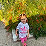 child, toddler, outdoor, greenery, plants, flowers, pavement, walking, casual_clothing, adidas, pink_shorts, sandals, pigtails, sunlight, daylight, nature, sidewalk, smiling, cute, portrait