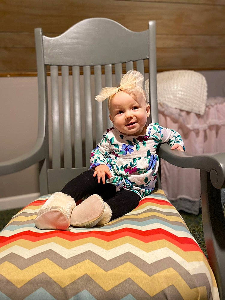 Remi is registered to the contest to win money with this photo: ankle, baby, baby_laughing, baby_toddler_clothing, child, comfort, flooring, foot, home_accessories, lap, linens, living_room, nose, person, room, sitting, sock, toddler