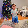 Lilya joined the competition — help win amazing prizes! blanket, blue_dress, carpet, child, christmas_tree, cozy, festive, furniture, happy, holiday_decorations, home, indoor, lights, living_room, ornaments, person, smiling, stocking, toddler, wooden_floor
