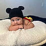Ethan is registered to the contest to win money with this photo: baby, infant, cute, hat, black_hat, mouse_ears, cushion, white_cushion, fluffy, soft, lying_down, indoors, skin, chubby, face, eyes, hand, portrait, child, blanket