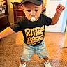 Elias is registered to the contest to win money with this photo: child, toddler, baby, portrait, indoors, standing, black_cap, pacifier, graphic_t_shirt, denim_shorts, sneakers, fashion, smiling, face, person, carpet, bedroom, dresser, door, home