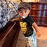 child, toddler, baby, portrait, standing, pacifier, baseball_cap, t_shirt, jeans, sneakers, bracelet, bedroom, bed, dresser, furniture, carpet, indoors, patterned_bedding, looking_at_camera, home