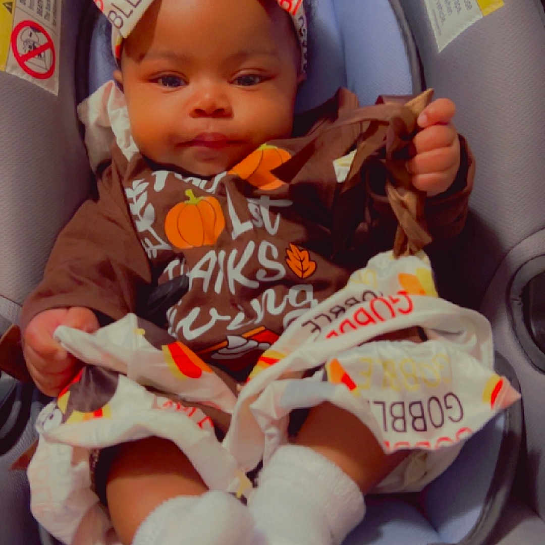 Lei'Kaci is registered to the contest to win money with this photo: baby, bodypart, bonnet, car, car_interior, carseat, clothing, face, finger, hand, hat, head, hosiery, person, photography, portrait, sock, toy, transportation, vehicle