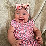 baby, smiling, headband, bow, romper, patterned_clothing, happy, infant, sitting, blanket, cozy, cute, child, face, hands, skin, indoors, portrait, closeup, wearing