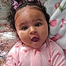 baby, infant, child, portrait, lying_down, wide_eyes, open_mouth, curly_hair, hair_bows, pink_onesie, hearts, floral_bedding, blanket, bedding, cozy, indoor, close_up, smiling, adorable, photography