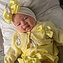 baby, infant, smile, yellow_outfit, bow, headband, bunny_patch, bed, pillow, blanket, cute, baby_clothes, soft_lighting, indoor, portrait, baby_girl, happy, child, newborn, cozy