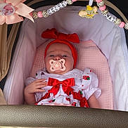 Dolce-Mai is registered to the contest to win money with this photo: baby, infant, stroller, pacifier, headband, bow, beads, decorations, clothing, red_bow, white_dress, pink_blanket, cute, child, person, indoor, closeup, adorable, soft_lighting, resting