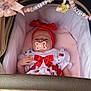 baby, infant, stroller, pacifier, headband, bow, beads, decorations, clothing, red_bow, white_dress, pink_blanket, cute, child, person, indoor, closeup, adorable, soft_lighting, resting