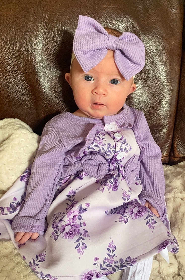 Dolce-Mai joined the competition — help win amazing prizes! baby, child, infant, headband, bow, purple, dress, floral_pattern, long_sleeves, buttons, sitting, blanket, leather_chair, curious_expression, face, hands, indoors, portrait, cute, soft_texture
