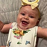baby, child, infant, smiling, happy, portrait, headband, bow, animal_print, dress, arms, eyes, face, lying_down, blanket, quilt, bed, indoors, close_up, photography